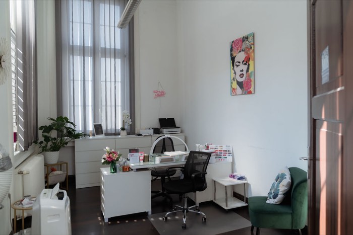 Heller Beratungsraum mit Frida-Kahlo-Bild, Farbkarten und grünem Sessel